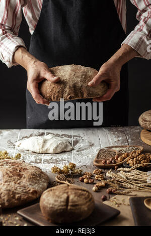 Irriconoscibile baker detiene appena sfornato organico rustico pagnotta di pane in mano Foto Stock