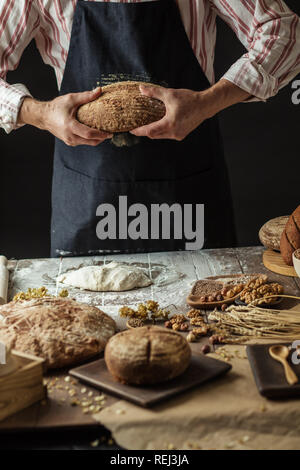 Irriconoscibile baker detiene appena sfornato organico rustico pagnotta di pane in mano Foto Stock