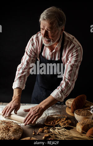 Sperimentato Baker uomo preparazione impasto per il pane fatto in casa in cucina. Foto Stock