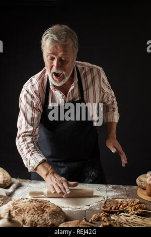 Sperimentato Baker uomo preparazione impasto per il pane fatto in casa in cucina. Foto Stock