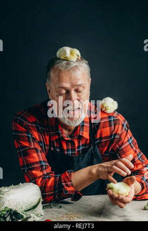 L'uomo alimentando il suo polli seduto sull'erba Foto Stock