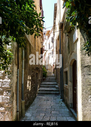 Strada stretta sulla isola di Korcula con gradini e una vista della cupola del duomo Foto Stock