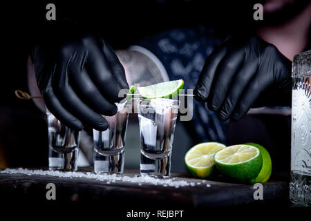 Aperitivo con gli amici nel bar, tre bicchieri di alcool con calce e sale per la decorazione. Scatti di tequila, il fuoco selettivo. Foto Stock