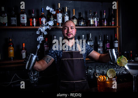 Il barman giocoliere getta un ghiaccio per cocktail al bar. Foto Stock