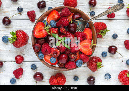Ciotola di estate bacche con yogurt o budino di Chia con fresche lamponi, fragole, ciliegie e mirtilli con un cucchiaio. Colazione sana. top v Foto Stock