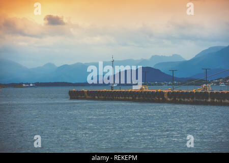 Bay nella luce della sera. Pier in mare e monti all'orizzonte. Alesund, Norvegia, Europa Foto Stock