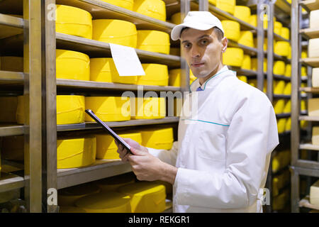 Ispettore rende note in foglio in corrispondenza del magazzino di formaggio Foto Stock