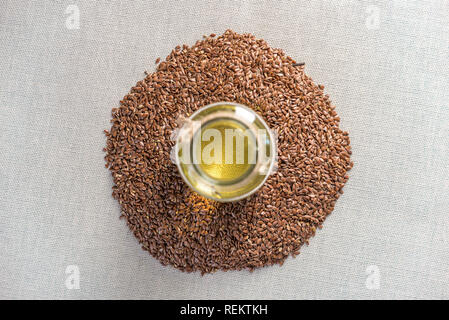 Semi di lino in una pila e semi di lino Olio d'oro in una bottiglia di vetro sul tavolo. Il concetto dieta sana con acidi grassi omega 3. Foto Stock