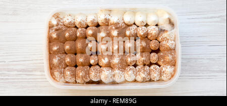 Il tiramisù gelato nella scatola di plastica, overhead. Appartamento laicale, da sopra, vista dall'alto. Foto Stock