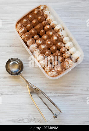 Il tiramisù gelato in scatola di plastica con paletta per gelato, overhead. Vista in pianta da sopra. Foto Stock