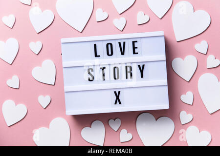 Una storia di amore lightbox messaggio con cuori bianco su uno sfondo rosa Foto Stock