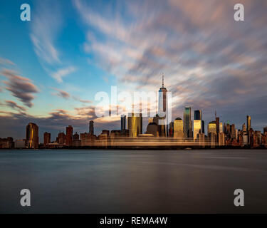 Città attraverso il fiume sotto le nuvole Foto Stock