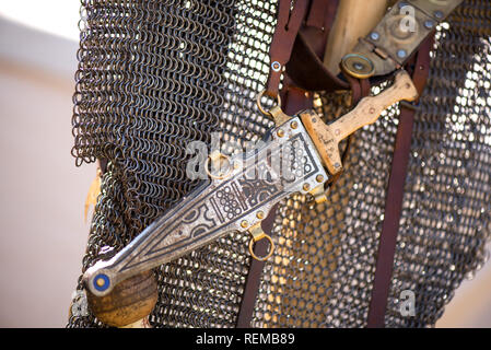 Argento o bronzo pugnale medievale con ornamenti attaccato alla catena armature, appeso nella striscia di cuoio. Soldati pronti per la battaglia. Rievocazione storica festival a Foto Stock