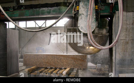 Elaborazione di granito in produzione. Il taglio di lastre di granito con una sega circolare. Foto Stock