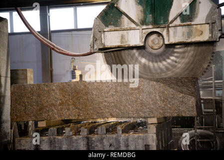 Elaborazione di granito in produzione. Il taglio di lastre di granito con una sega circolare. Foto Stock