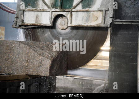 Elaborazione di granito in produzione. Il taglio di lastre di granito con una sega circolare. Foto Stock