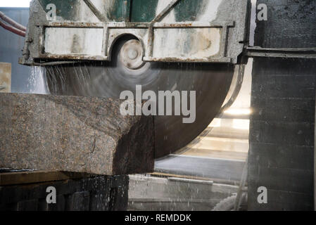 Elaborazione di granito in produzione. Il taglio di lastre di granito con una sega circolare. Foto Stock