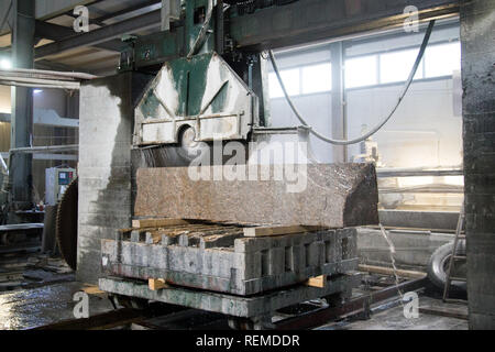 Elaborazione di granito in produzione. Il taglio di lastre di granito con una sega circolare. Foto Stock