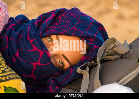 Giovani belle donne con velo di colore blu giace su uno zaino nel deserto di Thar. Foto Stock