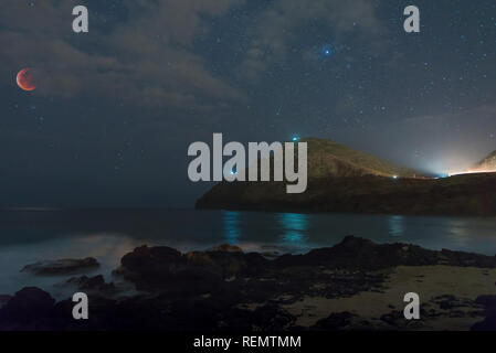 Super Lupo sangue Luna eclissata oltre Makapu'u Beach Park con misty acqua di lavaggio su roccia a Honolulu, Hawaii Foto Stock