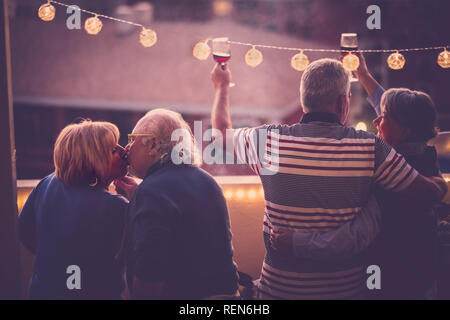 Romantico e amore concetto con due adulti senior giovane celebrare insieme a casa in una terrazza con vista sulla città - La tostatura con vino e baciare - matu Foto Stock