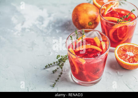 Campari o cocktail alcolici con fette di sangue siciliano di arance e rosso fresco succo di arancio su grigio chiaro sfondo concreto, copia spice, profondità minima Foto Stock