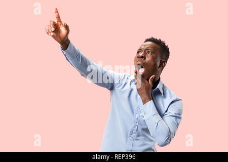 Wow. Maschio attraente a metà lunghezza verticale anteriore sul rosa backgroud studio. Giovani afro sorpreso emozionale uomo barbuto in piedi con la bocca aperta. Le emozioni umane, espressione facciale concetto. Colori alla moda Foto Stock