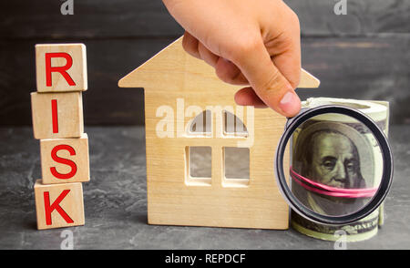 Miniatura casa in legno, dollari e l'iscrizione ' rischio'. Acquisto di una casa, un appartamento e rischi finanziari. Perdita di proprietà per il mancato pagamento. Prop Foto Stock