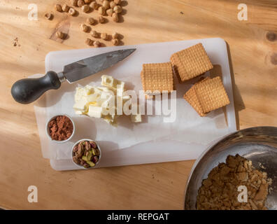 La fase di preparazione della tipica torta fatta in casa con il burro di cacao, zucchero e biscotti sbriciolati Foto Stock