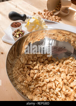 La fase di preparazione della tipica torta fatta in casa con il burro di cacao, zucchero e biscotti sbriciolati Foto Stock