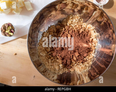 La fase di preparazione della tipica torta fatta in casa con il burro di cacao, zucchero e biscotti sbriciolati Foto Stock