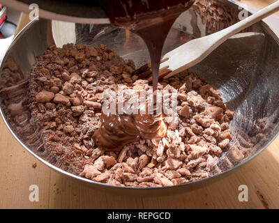 La fase di preparazione della tipica torta fatta in casa con il burro di cacao, zucchero e biscotti sbriciolati Foto Stock