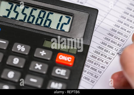 Close-up di calcolatrice e maschio con mano la penna sul documento finanziario Foto Stock