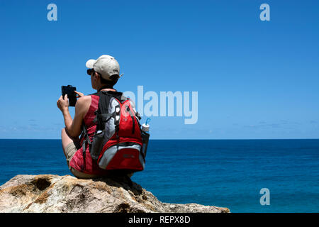 Una giovane donna di scattare una fotografia con un telefono a nord Gorge a piedi, Point Lookout, North Stradbroke Island, Queensland, Australia Foto Stock