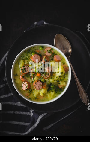 Stufato di carne con verdure fresche e salsicce al buio su un sfondo moody Foto Stock