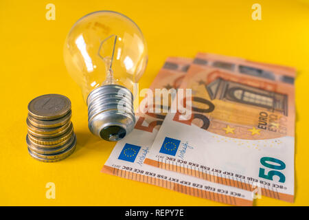 La lampadina della spia e unione di banconote e monete in euro. E27. Spiralato filamenti di tungsteno. Foto Stock