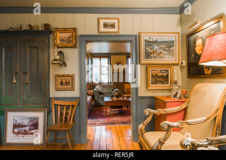Vecchia sedia in legno e poltroncina imbottita in parlatorio sala decorata con vari dipinti e la porta che conduce al soggiorno all'interno di circa 1805 home Foto Stock