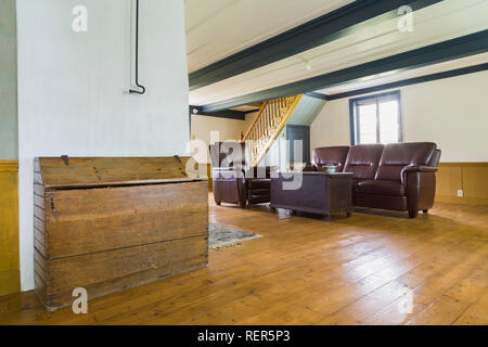 Soggiorno con la Borgogna divano in pelle, poltrona reclinabile, cassa di legno tavolino, legna da ardere scatola di archiviazione, Tavoloni Abete rosso all'interno di un vecchio 1809 home Foto Stock