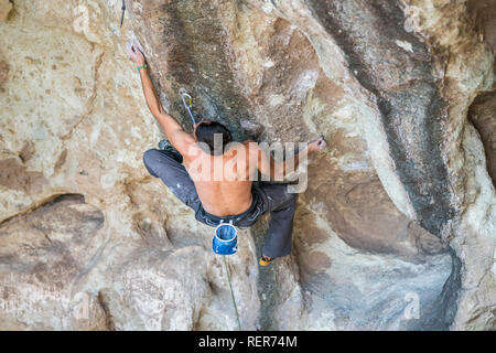 Praticare l'arrampicata su roccia sport estremo all'interno delle montagne Ande in una scogliera. Un arrampicatore maschio fa i movimenti duri con tenacia e fiducia Foto Stock