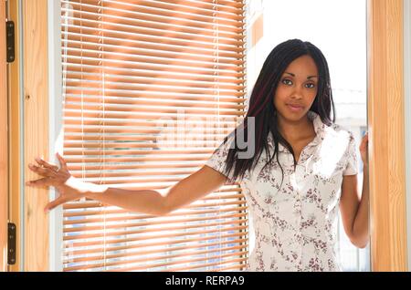 Giovane e bella di carnagione scura donna entrando in una stanza retroilluminati da una giornata di sole Foto Stock