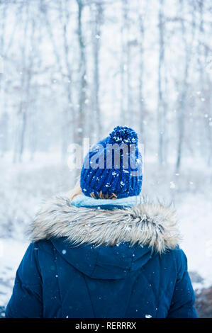 Donna con blu cappotto invernale e hat sotto la neve in natura Foto Stock