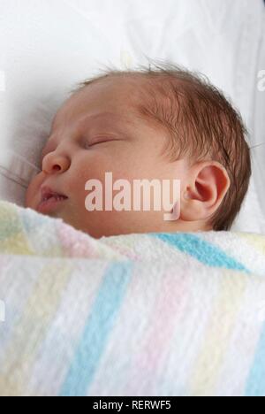 Un neonato addormentato in swaddling coperte Foto Stock