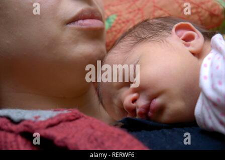 Un neonato di dormire sulla sua madre al torace Foto Stock