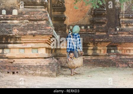 Donna birmano che porta il suo ragazzo in un cestello, Bagan, MYANMAR Birmania Foto Stock