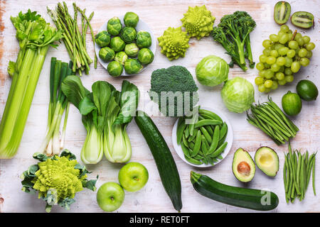 Mangiare sano concetto vegan. Verdure verdi frutti sul tavolo bianco broccoletti piselli avocado fagioli zucchine cavolo cinese sedano mela uva, top v Foto Stock