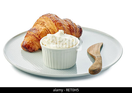 Croissant fresco e una ciotola di crema di formaggio sulla piastra su sfondo bianco Foto Stock