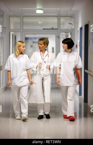 Medico donna parlando con due infermiere in un ospedale corridoio Foto Stock