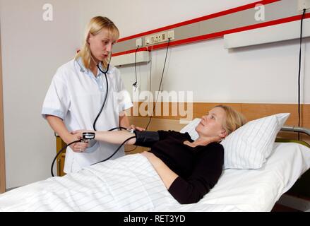L'infermiera controllando la pressione del sangue di un paziente in un ospedale Foto Stock