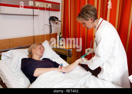 Medico di prendere un campione di sangue da un paziente in un ospedale Foto Stock