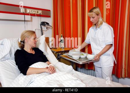 Infermiere portando un paziente in un letto di ospedale il pranzo Foto Stock